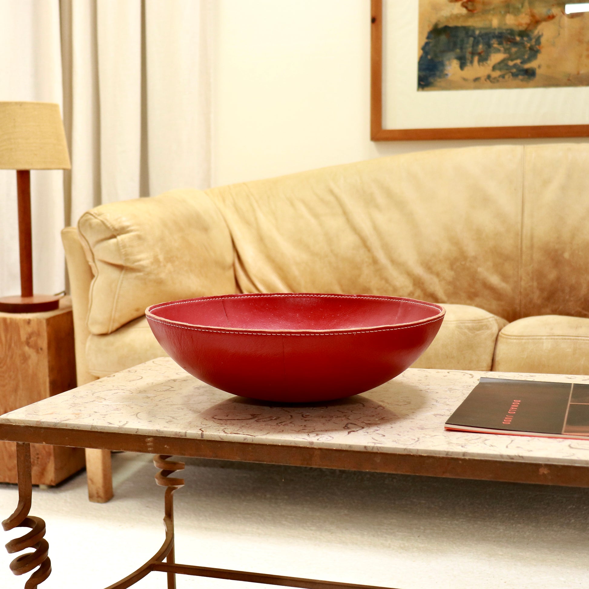 Large vintage red leather bowl with stitched rim on marble coffee table