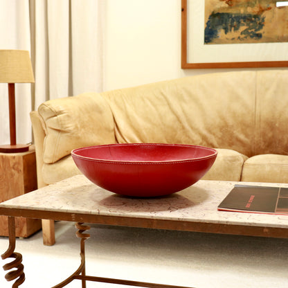 Large vintage red leather bowl with stitched rim on marble coffee table