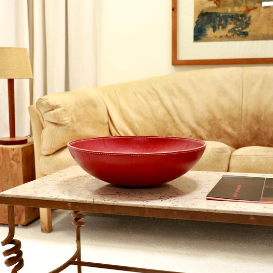 Large vintage red leather bowl with stitched rim on marble coffee table