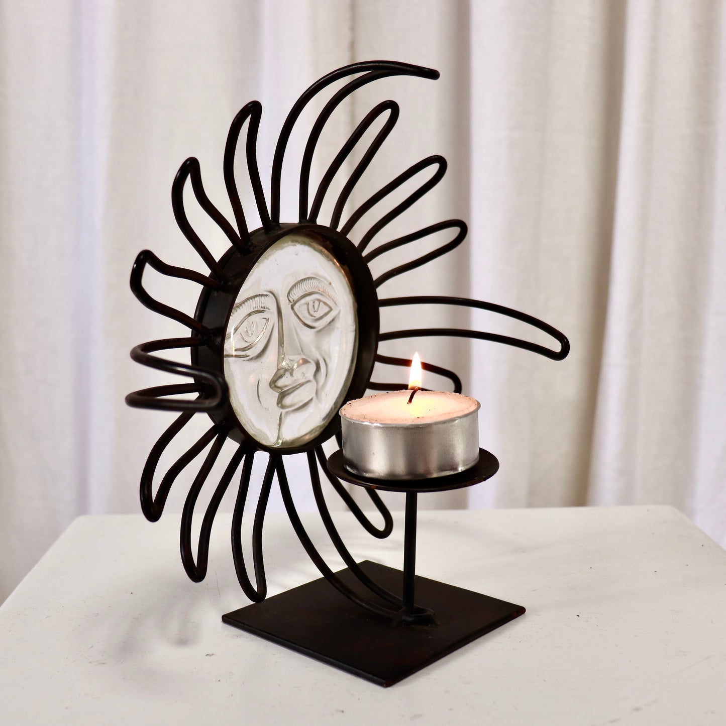 Detail of glass face with tealight saucer beside it.