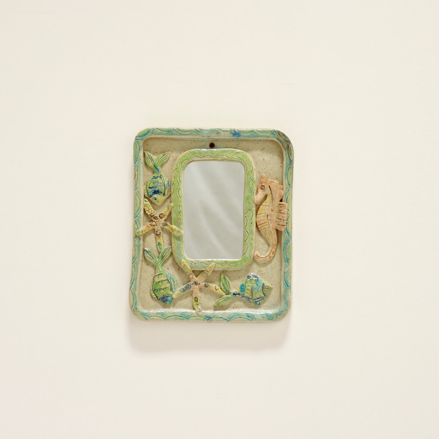 “Vintage ceramic mirror with relief seahorse and fish, front view”