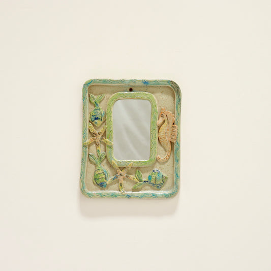 “Vintage ceramic mirror with relief seahorse and fish, front view”