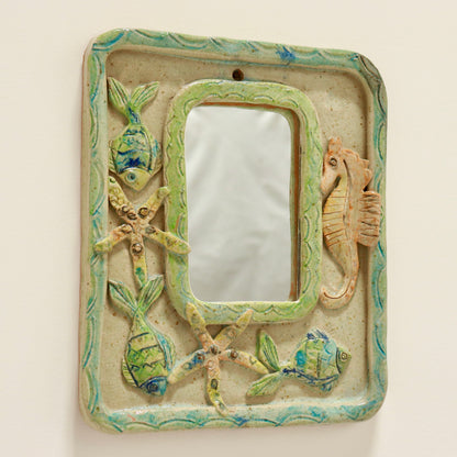 “Angled view of signed folk art ceramic mirror showing underwater motifs”