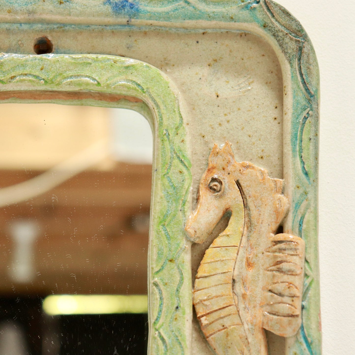 “Detail of seahorse and glazed border on vintage ceramic mirror”