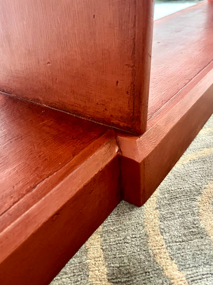 Close-up of a reddish-brown wooden furniture corner meeting a patterned gray and beige carpet.
